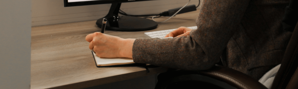 Close up shot of a hand writing notes at a desk
